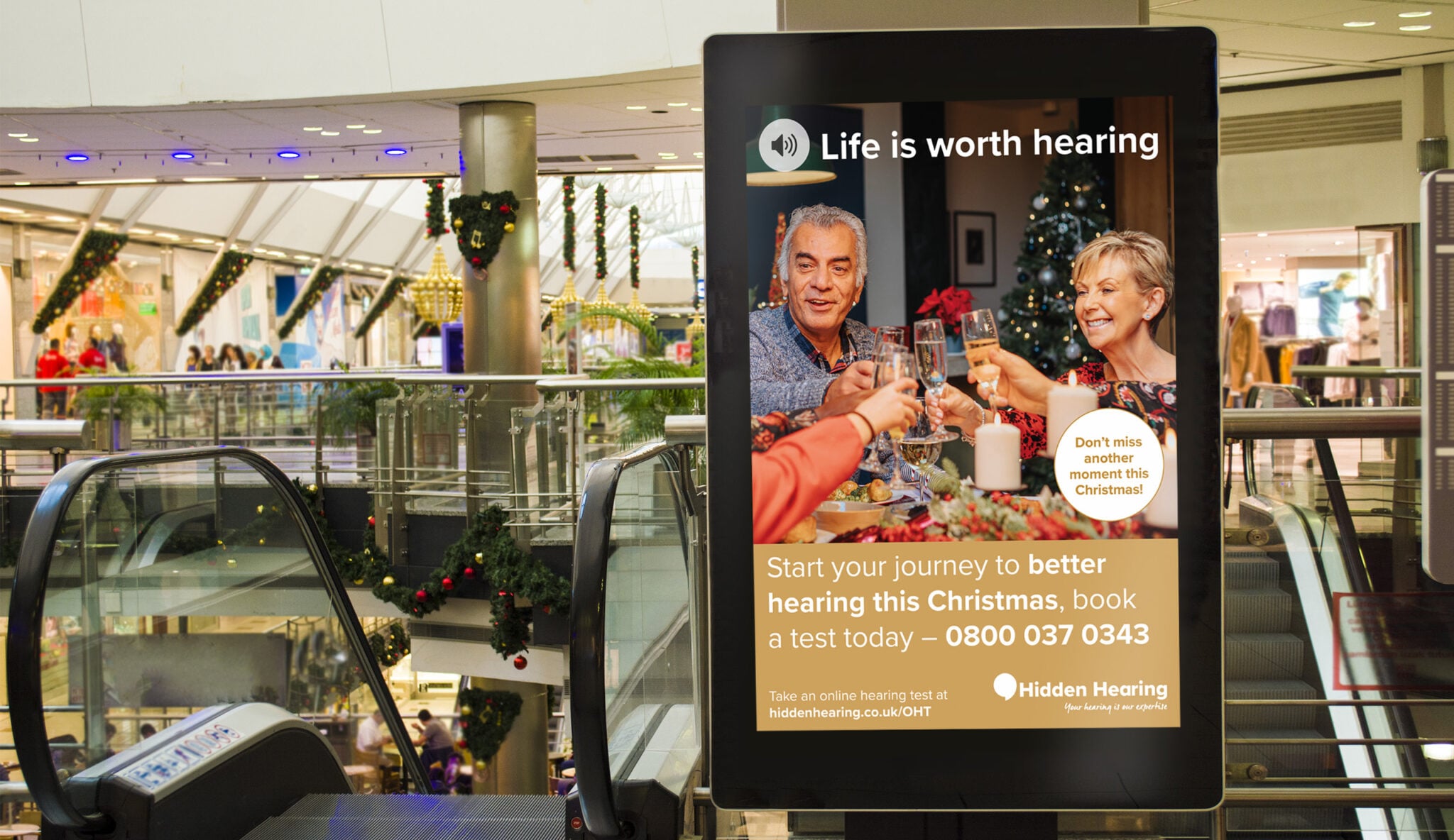 Hidden Hearing campaign photography — Life Is Worth Hearing on an advertising display board in a shopping centre