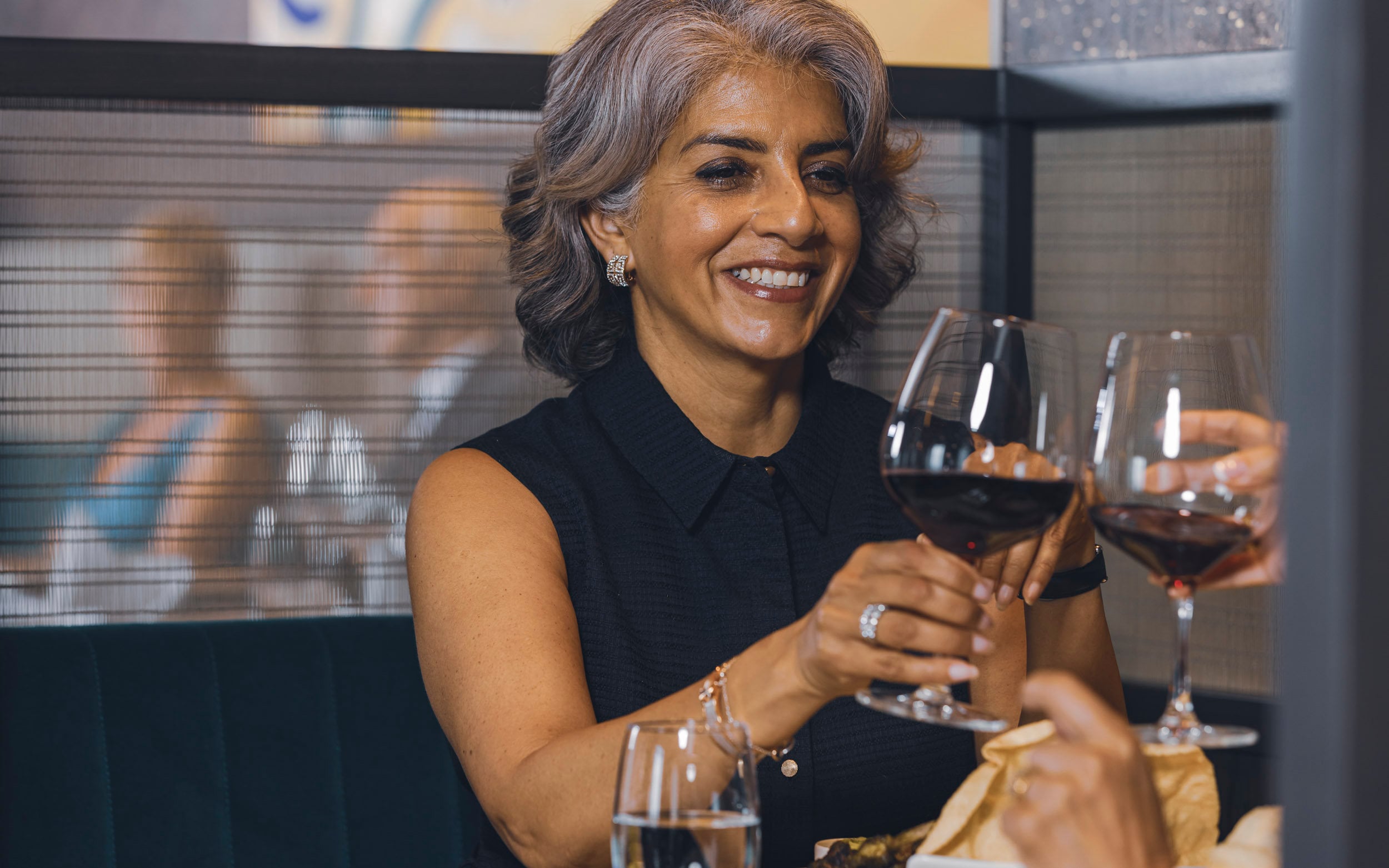 Saga cruise dining photography — guest toasting with a red wine glass in a fine-dining restaurant