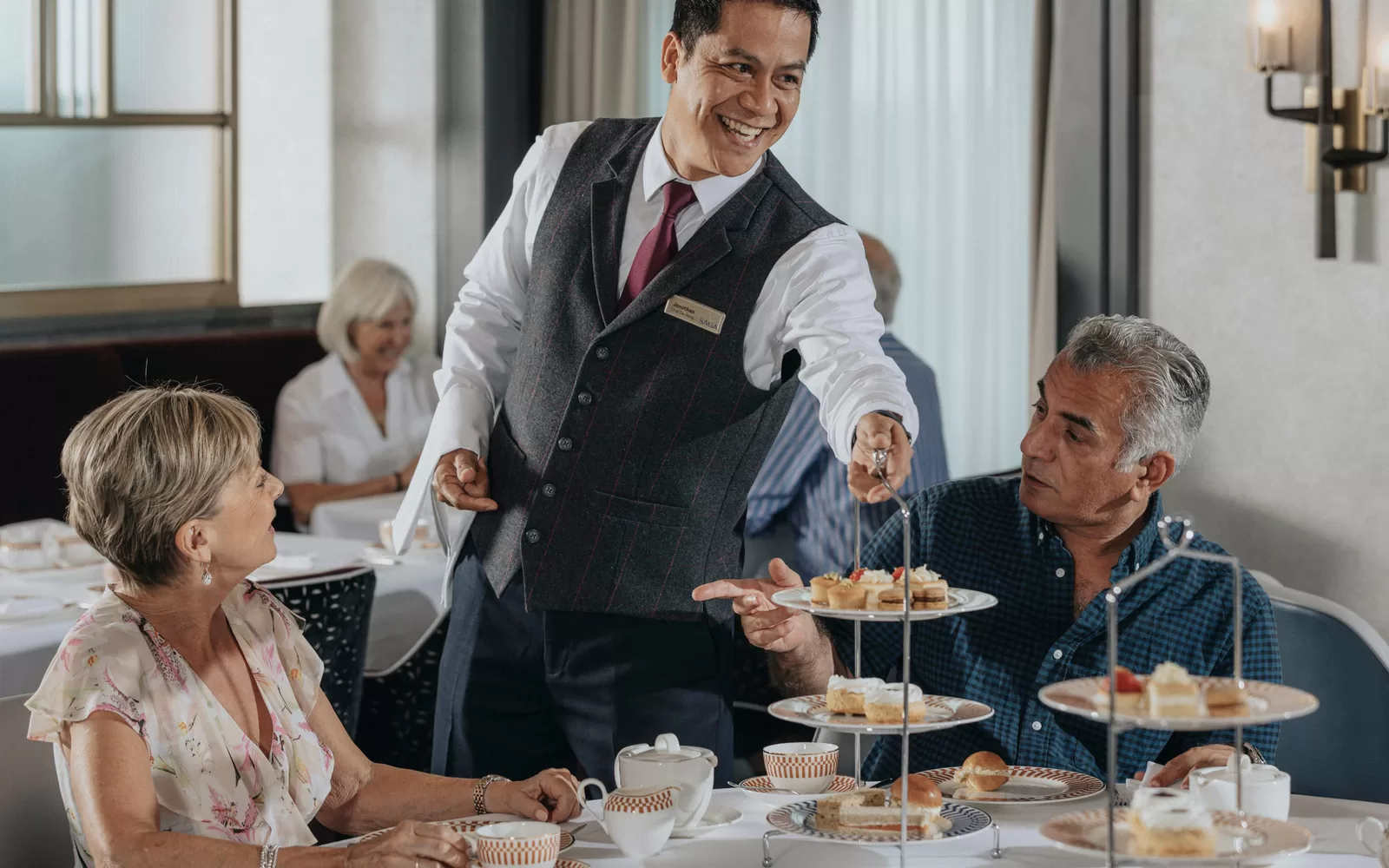 Saga cruise dining photography — afternoon tea service with a tiered cake stand presented to a couple