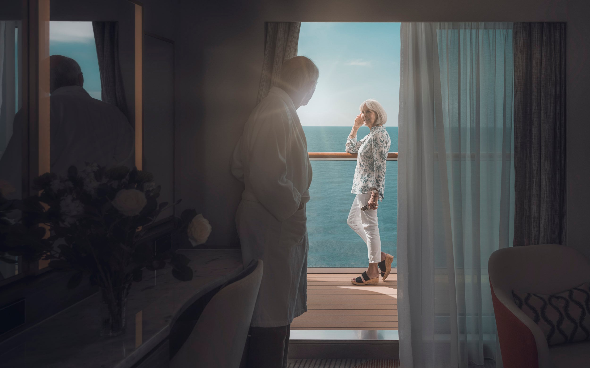Saga cruise stateroom photography — couple on a sunlit private balcony with open ocean view
