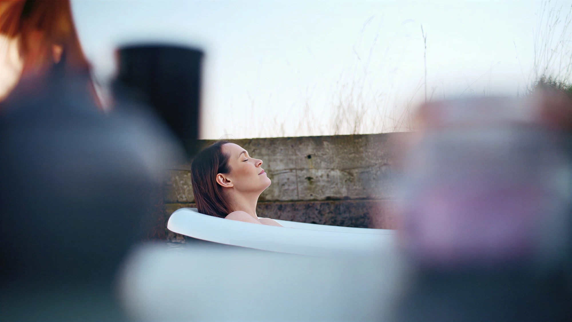 Visit Kent tourism photography — woman relaxing in an outdoor bath overlooking the Kent coast
