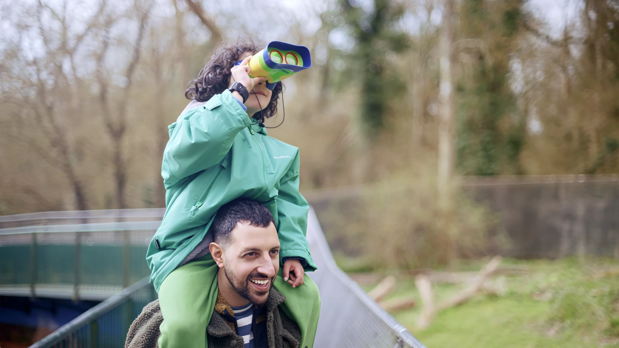 Visit Kent tourism photography — father carrying child on his shoulders with toy binoculars in a wildlife park