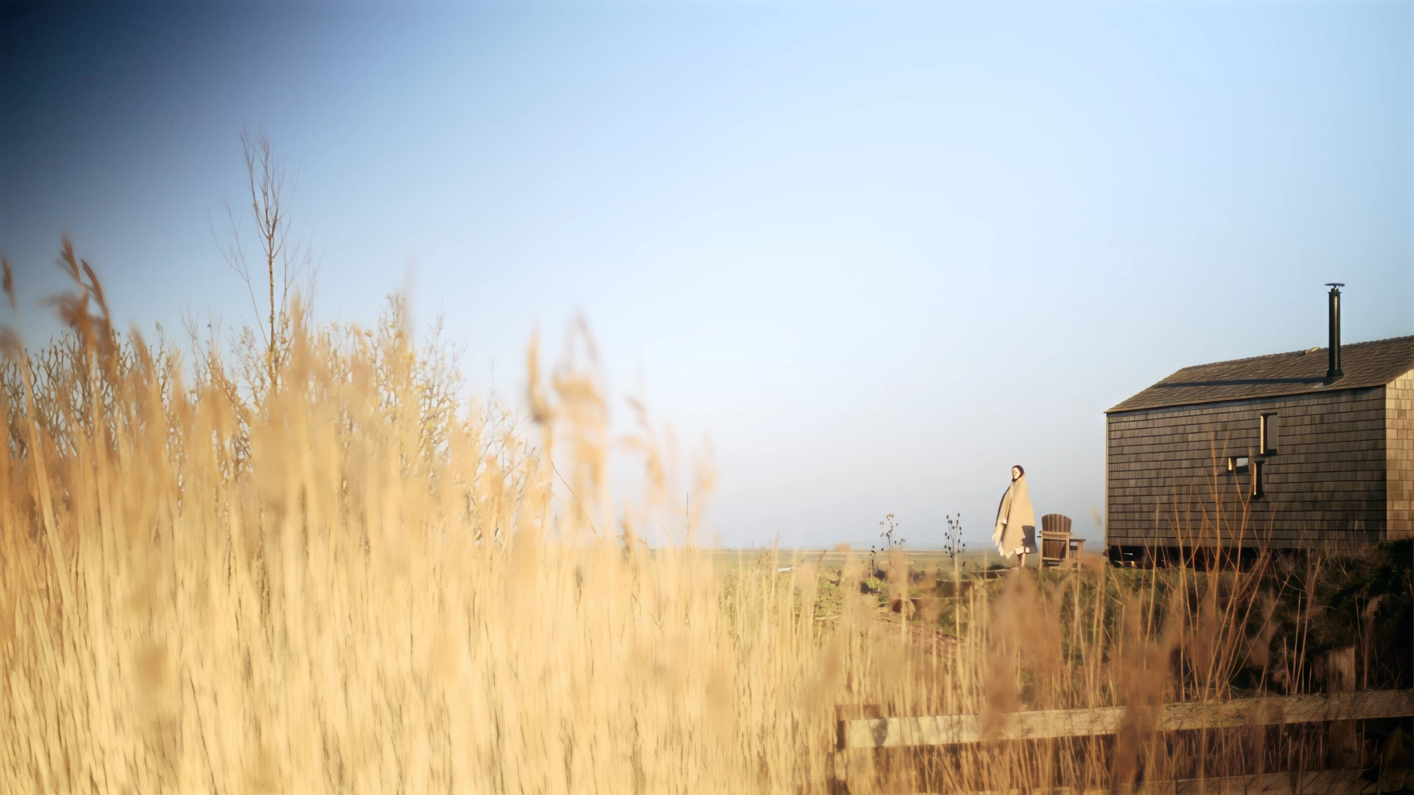 Visit Kent tourism photography — solo figure wrapped in a blanket beside a shepherd's hut at golden hour